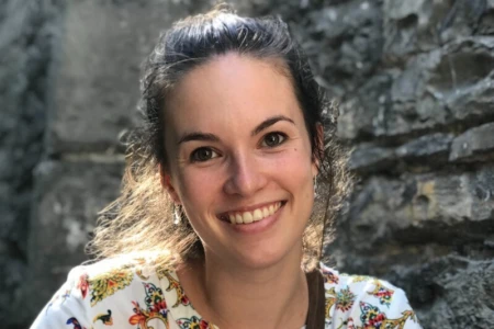 Profielfoto van een vrouw met een wit-gekleurd hemd en een grijze muur op de achtergrond